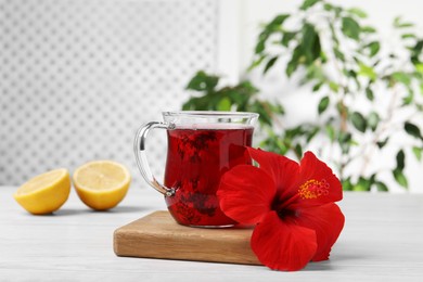Delicious hibiscus tea and beautiful flower on white wooden table