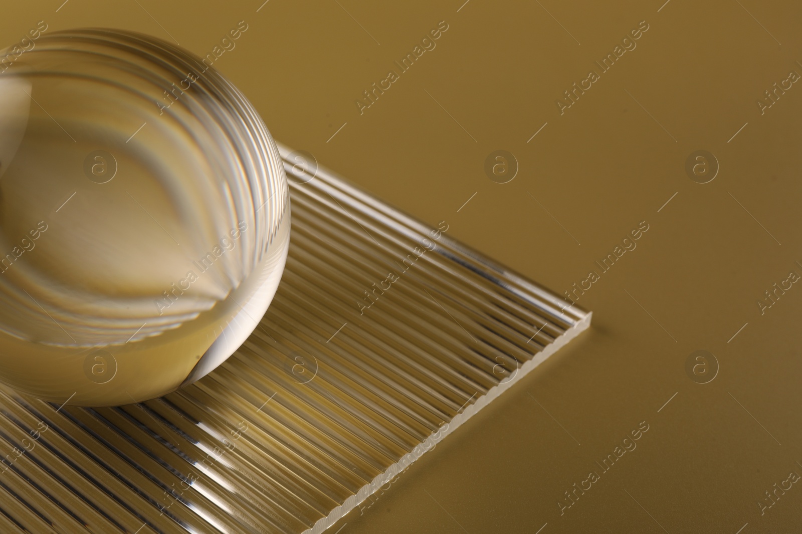 Photo of Transparent glass ball on yellow background, closeup. Space for text