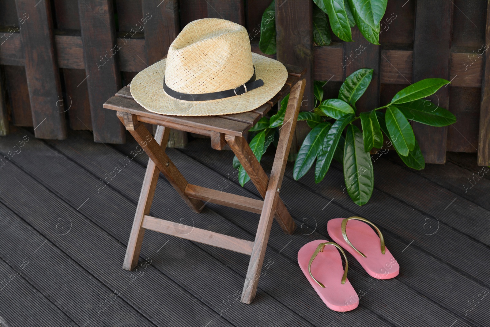 Photo of Stylish hat and flip flops near wooden fence. Beach accessories