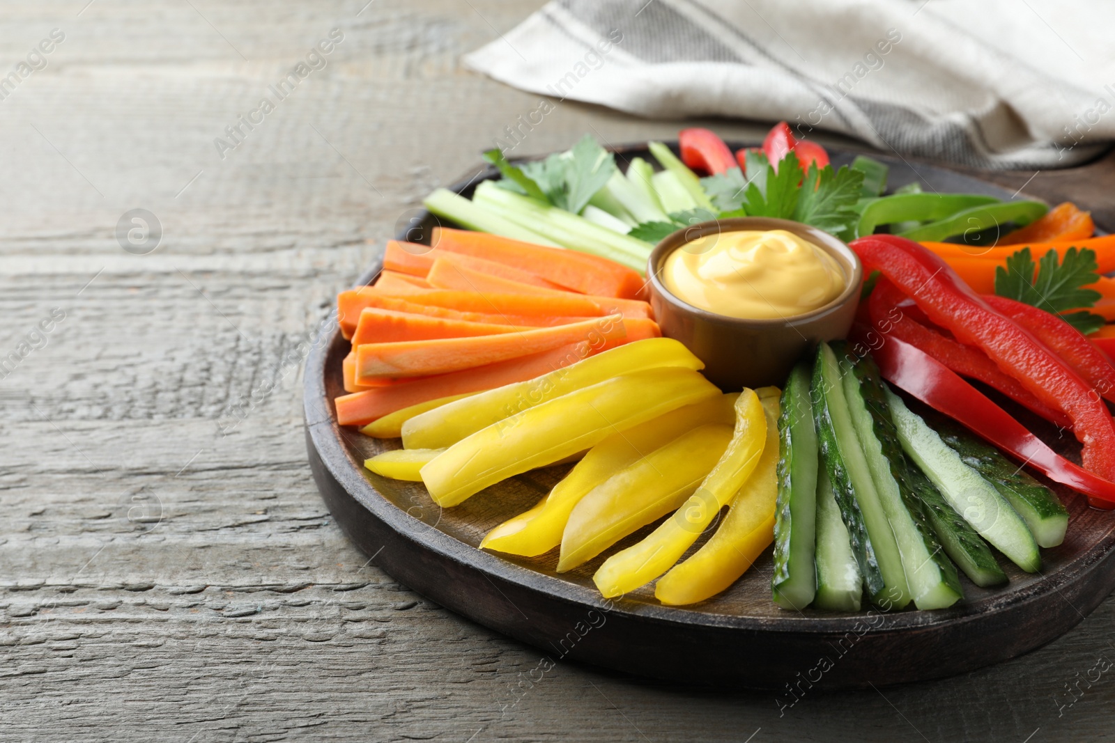 Photo of Different vegetables cut in sticks and dip sauce on wooden table, closeup