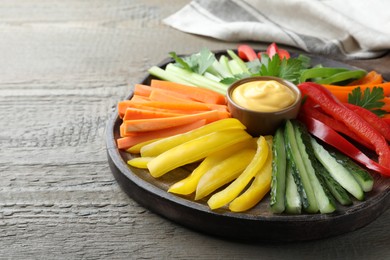 Photo of Different vegetables cut in sticks and dip sauce on wooden table, closeup