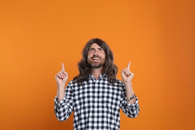 Photo of Hippie man pointing upwards on orange background