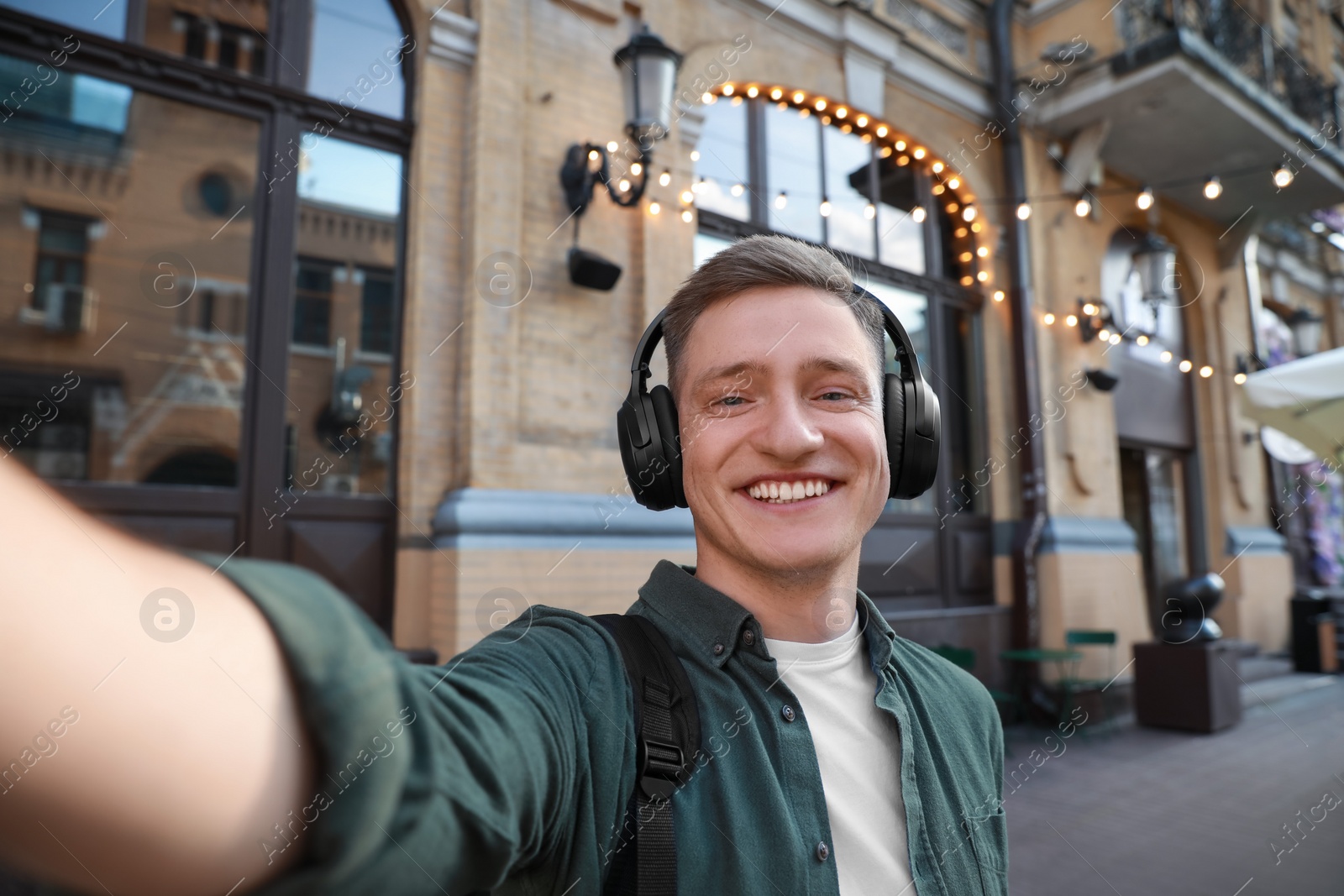 Photo of Smiling man in headphones taking selfie outdoors