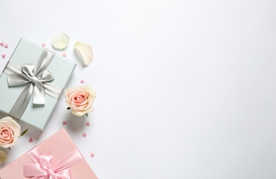 Photo of Elegant gift boxes and beautiful flowers on white background, flat lay. Space for text
