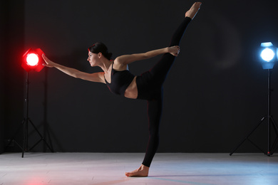 Young professional acrobat exercising in dark studio