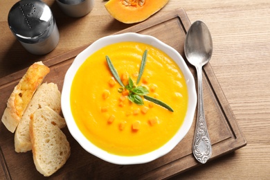 Flat lay composition with bowl of pumpkin soup on wooden background