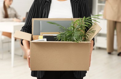 Photo of Unemployment problem. Woman with box of personal belongings in office, closeup