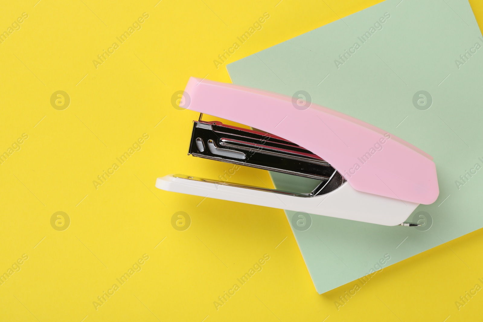 Photo of New stapler on yellow background, top view. Space for text