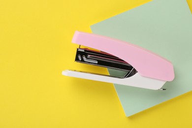 New stapler on yellow background, top view. Space for text