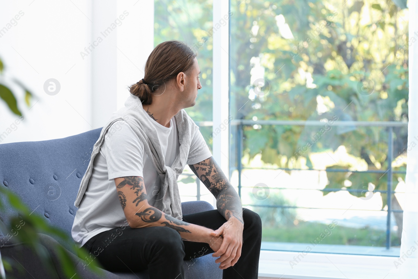 Photo of Young man with stylish tattoos at home. Space for text