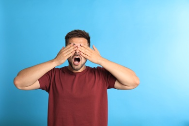 Young man being blinded on blue background