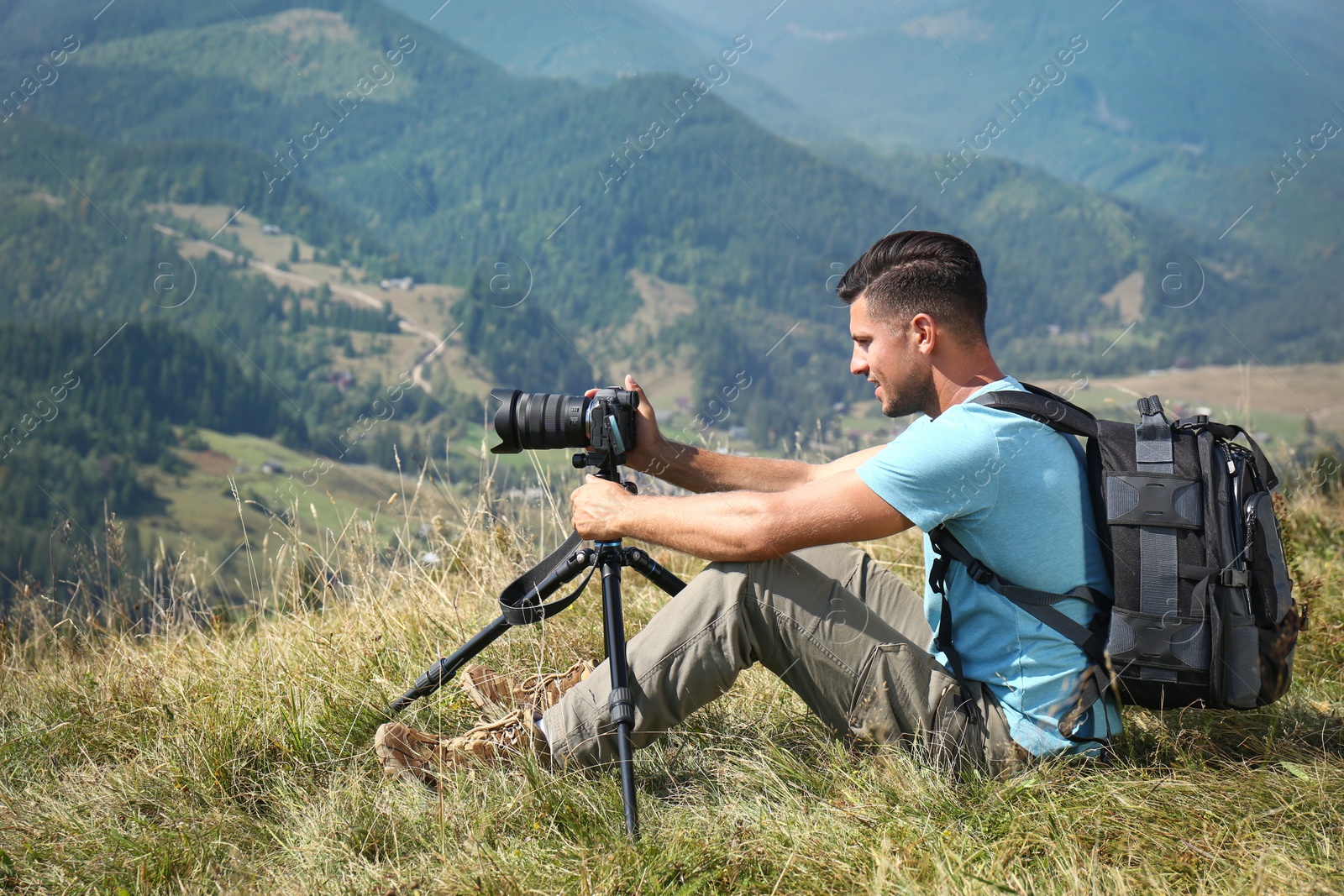 Photo of Man taking photo of mountain landscape with modern camera on tripod outdoors