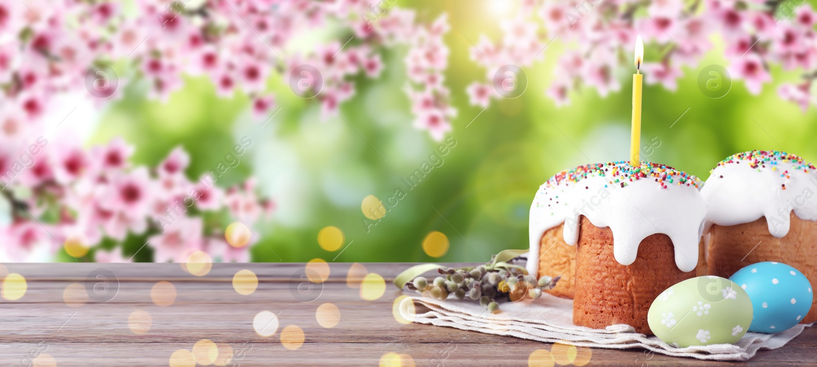 Image of Traditional Easter cakes and eggs on wooden table outdoors, space for text. Banner design