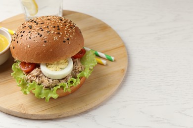 Photo of Delicious sandwich with tuna, boiled egg and vegetables on white wooden table, space for text