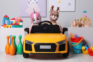 Photo of Child's electric car with other toys near light wall in play room