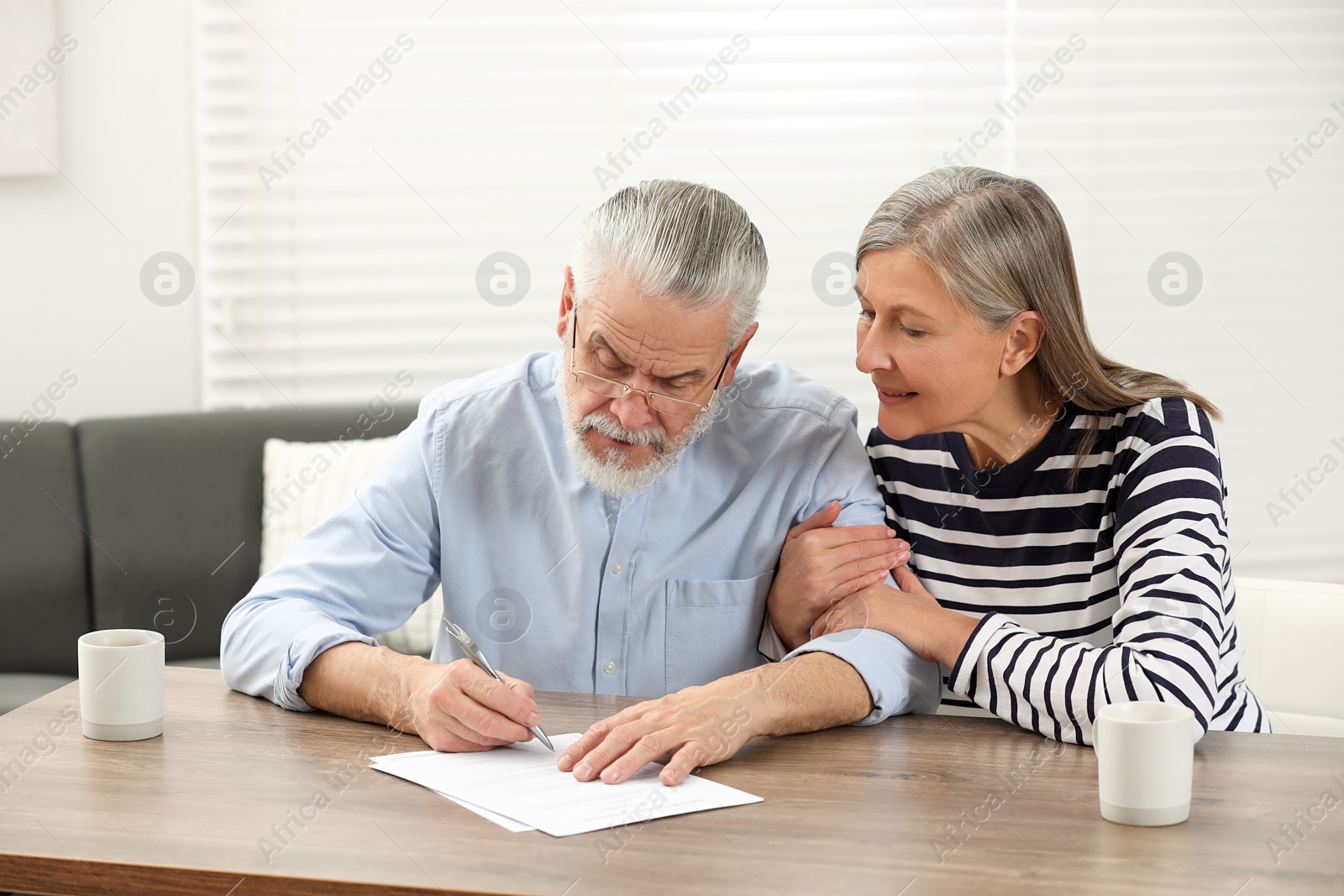 Photo of Senior couple signing Last Will and Testament indoors