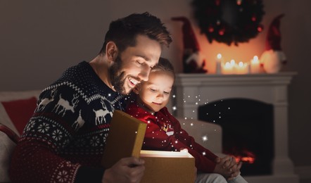 Image of Father and his cute daughter opening gift box with magical light at home. Christmas celebration