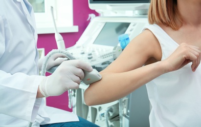 Photo of Doctor conducting ultrasound examination of elbow joint in clinic, closeup