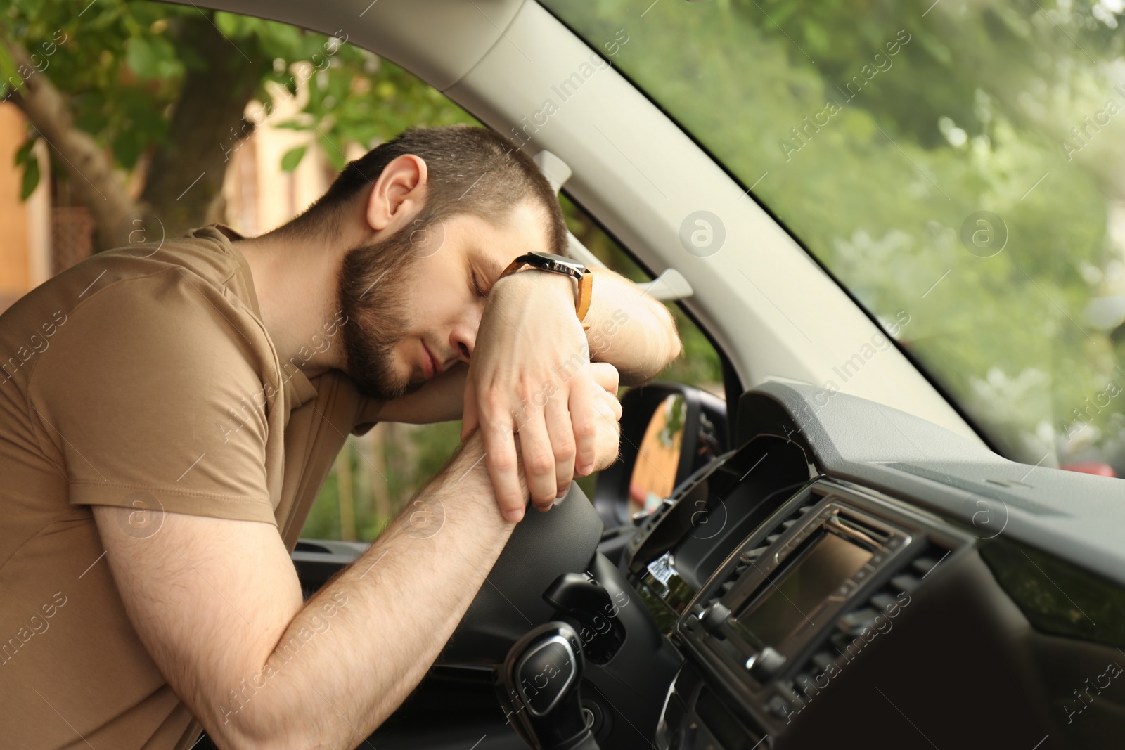 Photo of Tired man sleeping on steering wheel in his car