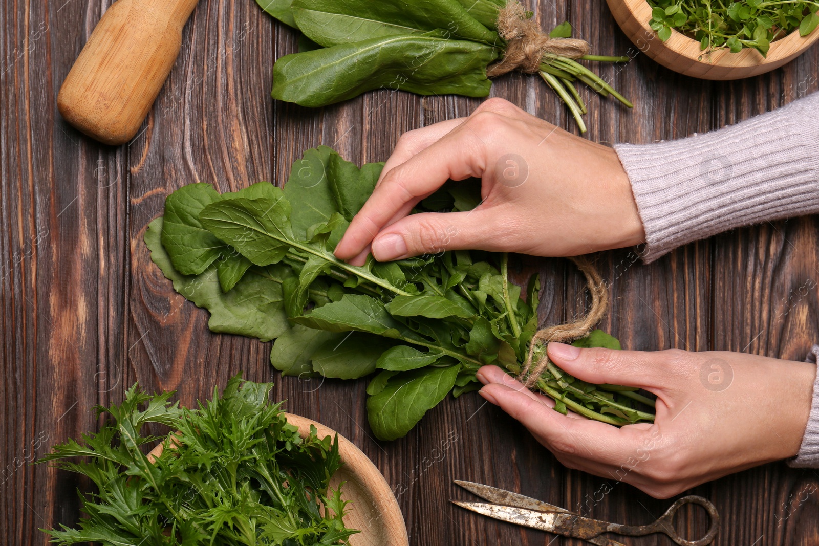 Photo of Woman with fresh green herbs at wooden table, top view