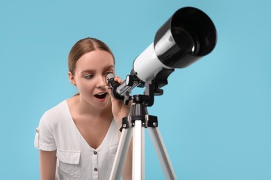 Photo of Emotional astronomer looking at stars through telescope on light blue background