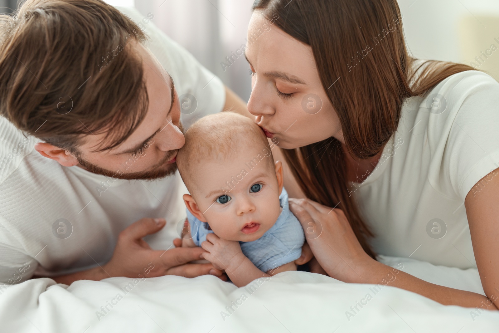 Photo of Happy family. Parents with their cute baby on bed indoors