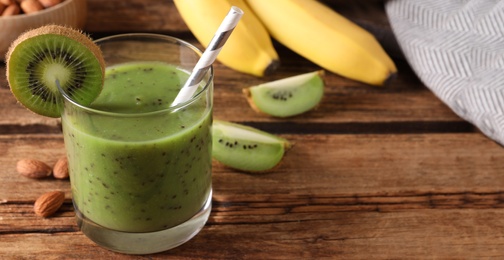 Photo of Delicious kiwi smoothie and ingredients on wooden table, closeup. Space for text