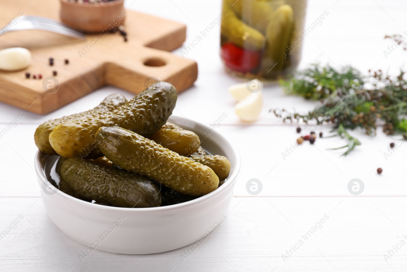 Photo of Tasty pickled cucumbers on white wooden table, space for text