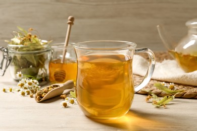Photo of Freshly brewed tea and dried herbs on white wooden table
