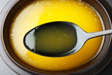 Spoon of clarified butter over bowl, closeup