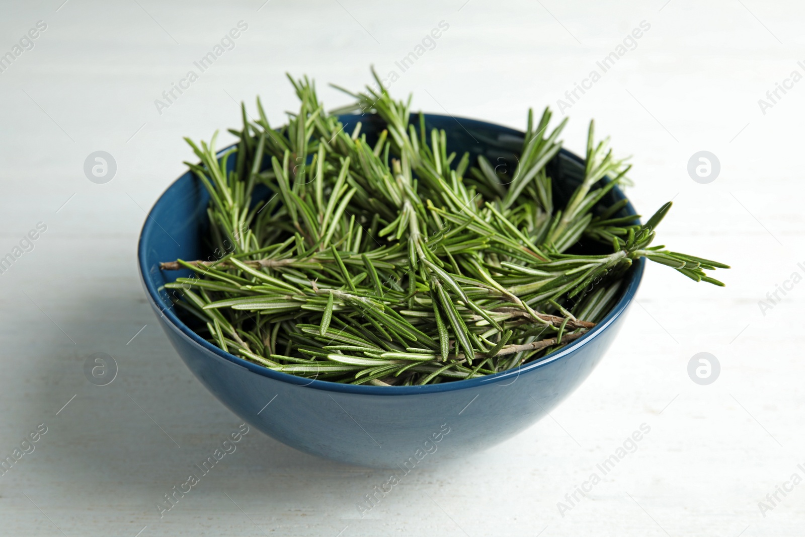 Photo of Bowl with fresh rosemary twigs on wooden table