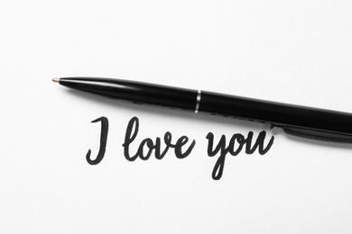 Text I Love You and pen on white background, top view