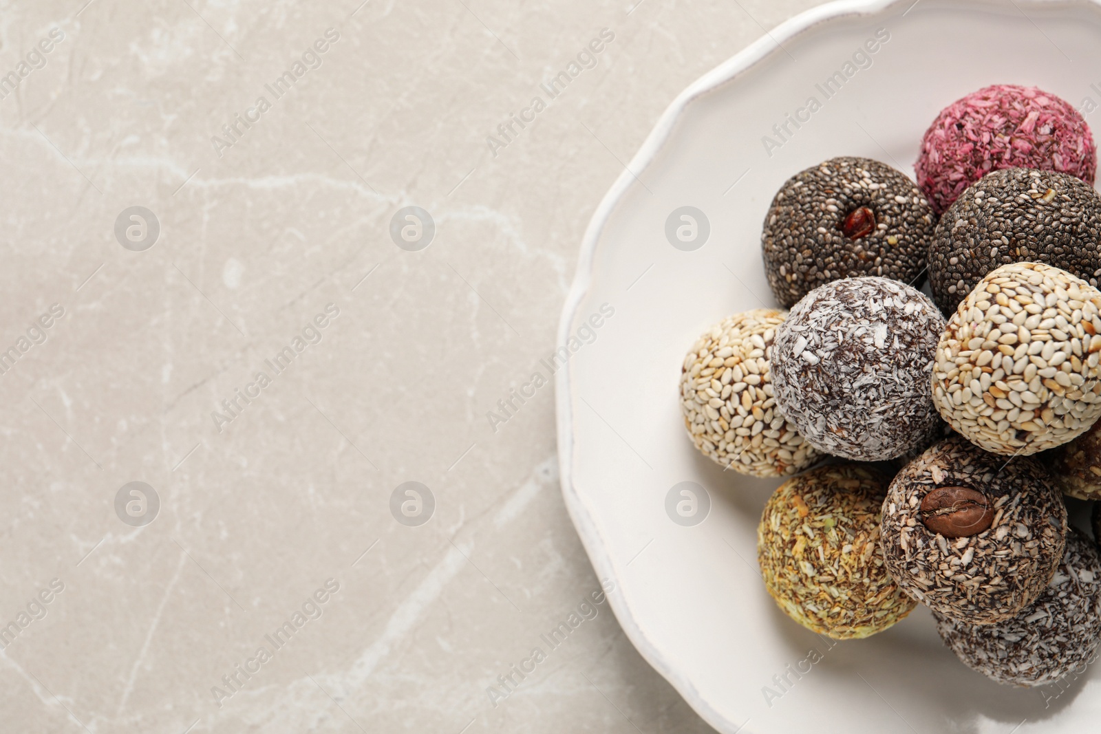 Photo of Different delicious vegan candy balls on light grey marble table, top view. Space for text