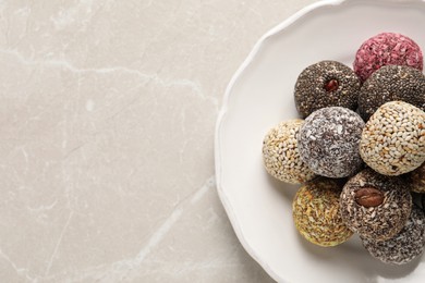 Photo of Different delicious vegan candy balls on light grey marble table, top view. Space for text