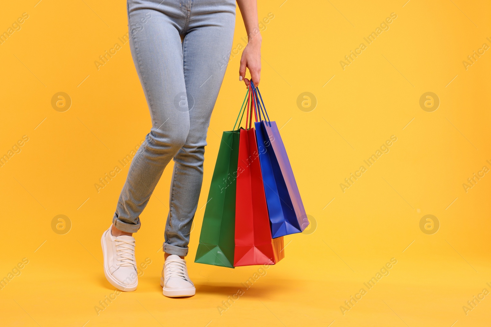 Photo of Woman with shopping bags on yellow background, closeup. Space for text