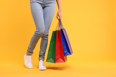 Woman with shopping bags on yellow background, closeup. Space for text