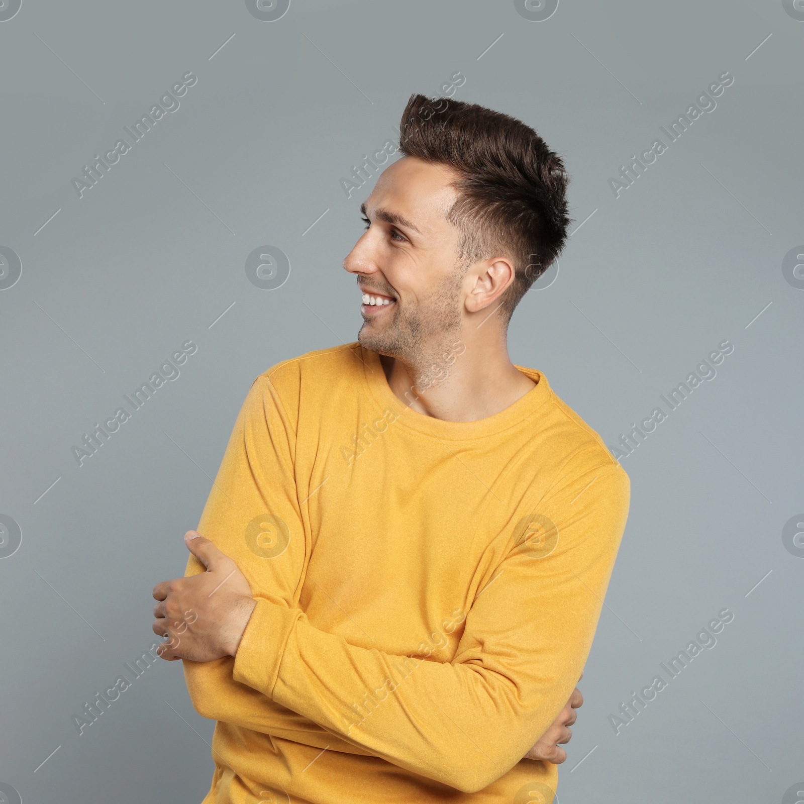 Photo of Happy young man in yellow sweatshirt on grey background. Winter season