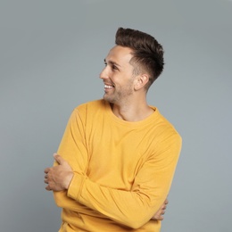 Photo of Happy young man in yellow sweatshirt on grey background. Winter season