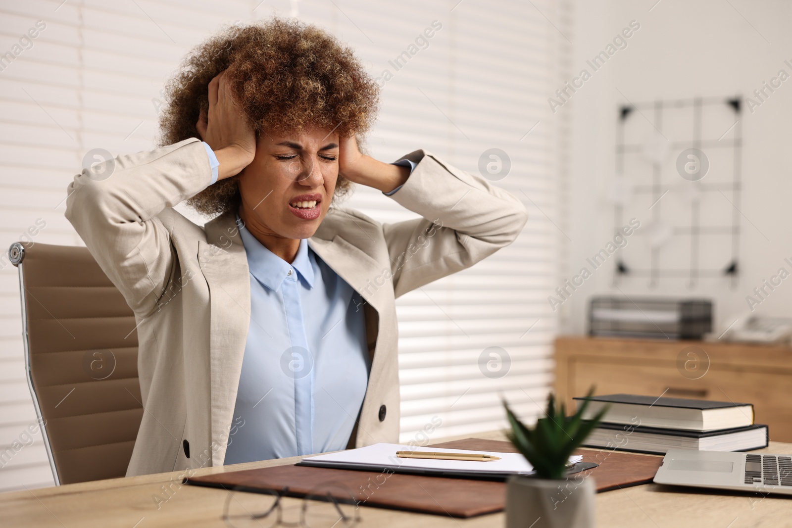 Photo of Woman suffering from headache at workplace in office