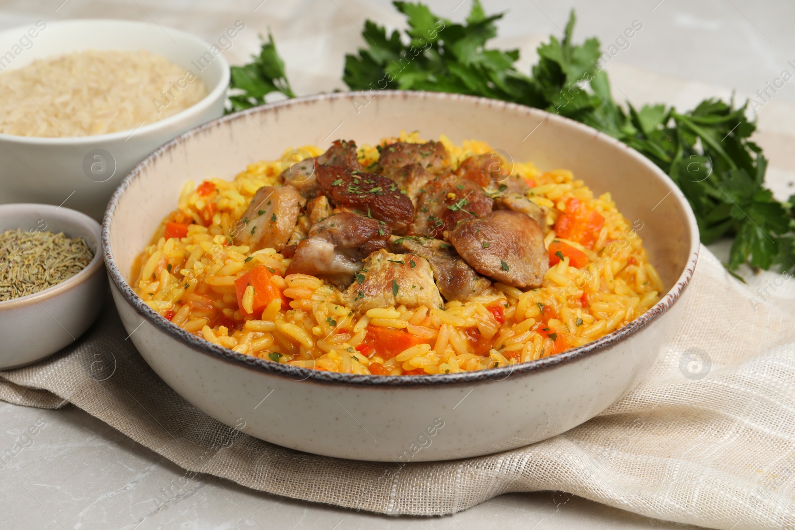 Photo of Delicious pilaf with meat and ingredients on light grey table, closeup