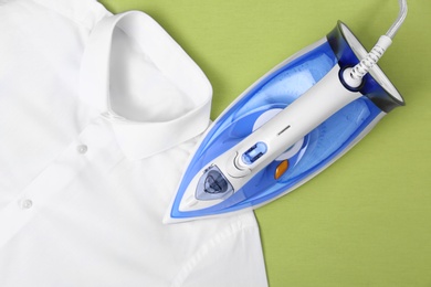 Modern electric iron and shirt on color background, top view with space for text. Laundry day