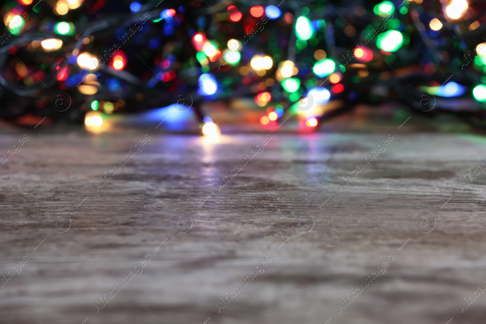 Photo of Wooden table and blurred Christmas lights on background