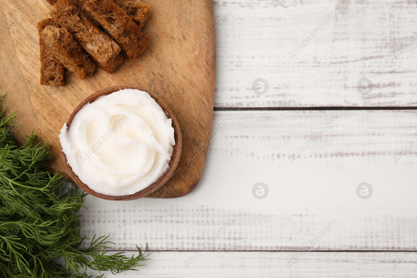 Photo of Delicious pork lard in bowl, crispy rusks and dill on white wooden table, flat lay