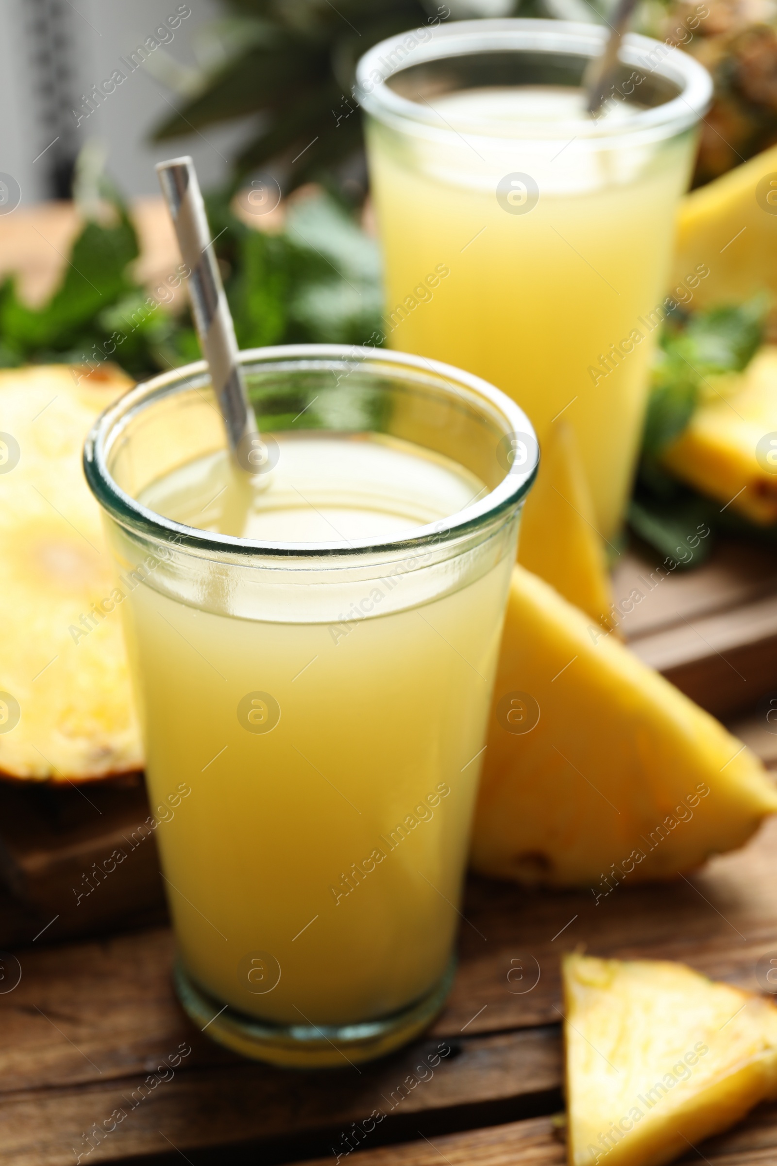 Photo of Delicious pineapple juice and fresh fruit on wooden table