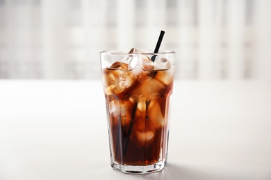 Photo of Glass of refreshing cola with ice on white table