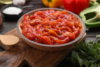 Bowl of delicious lecho on black wooden table, closeup