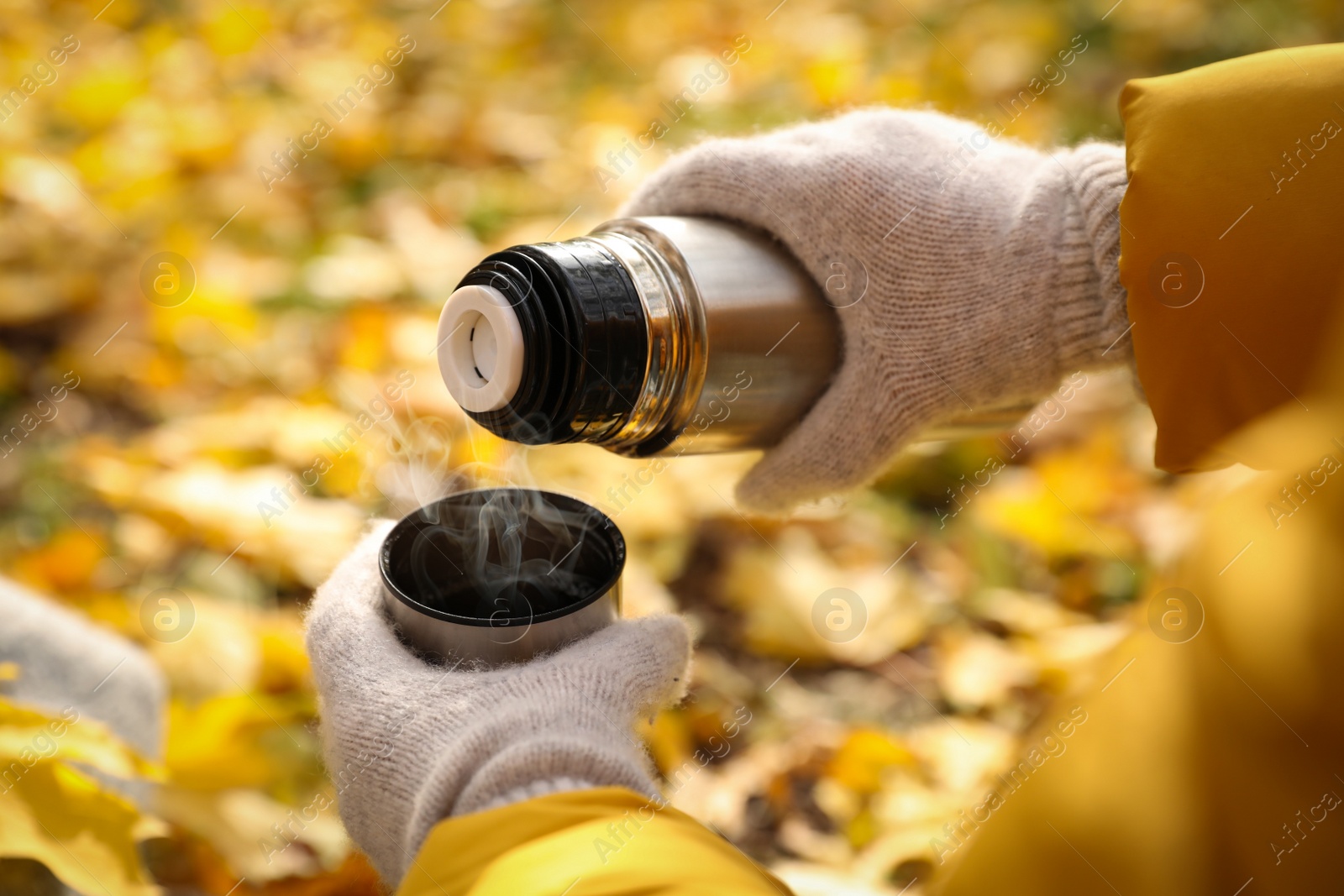 Photo of Woman pouring drink from thermos into cap outdoors, closeup