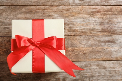 Photo of Elegant gift box with bow on wooden background, top view