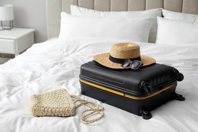 Photo of Suitcase packed for trip and summer accessories on bed indoors