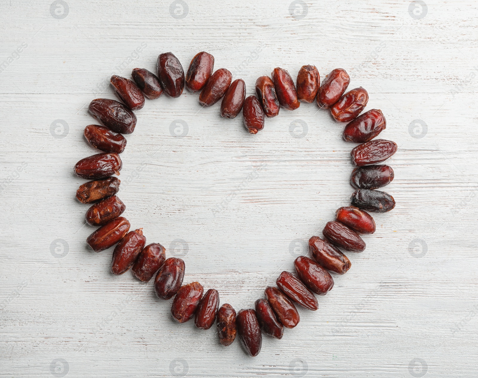 Photo of Frame made of sweet dried date fruits on wooden background, top view with space for text